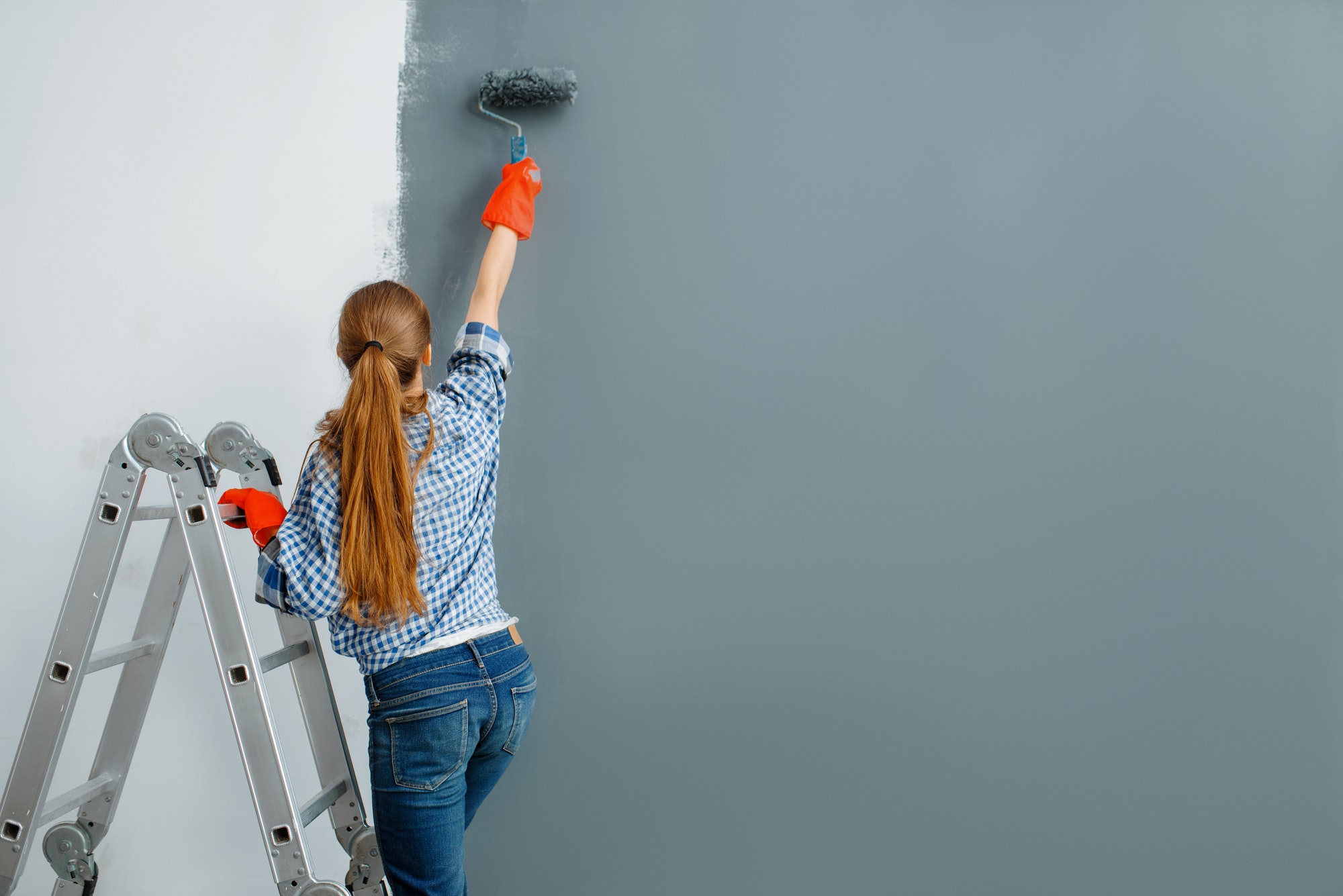 Female house painter paints walls indoor